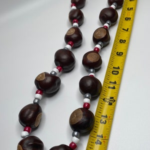 May include: A necklace made of brown buckeye nuts and white and gray beads. The necklace is approximately 16 inches long.