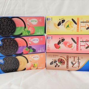 May include: A stack of eight boxes of Oreo cookies with different flavours. The boxes are blue, yellow, pink, and brown. Each box features a different Oreo cookie flavour, including peach, blueberry, and strawberry. The boxes are labelled "奥利奥" which is the Chinese word for Oreo.