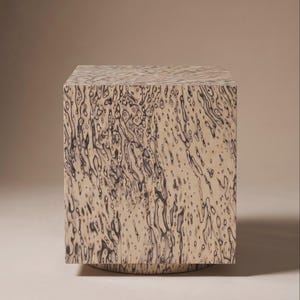 Può includere: Un tavolino quadrato beige con un motivo unico di forme organiche grigio scuro. Il tavolo ha una forma solida a blocchi e poggia su una base circolare, creando un'estetica moderna e artistica.