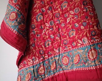 May include: Red and teal floral patterned quilt with a quilted texture. The quilt has a border of teal and red floral designs.