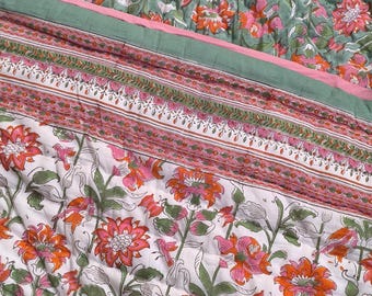 Può includere: Una trapunta di cotone bianco con un motivo floreale in tonalità di rosa, arancio e verde. La trapunta ha un bordo con un motivo ripetuto di rosa, arancio e verde.
