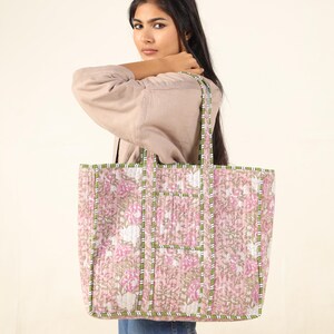 May include: A large pink and green floral tote bag with a quilted design. The bag has a wide base and two long straps.