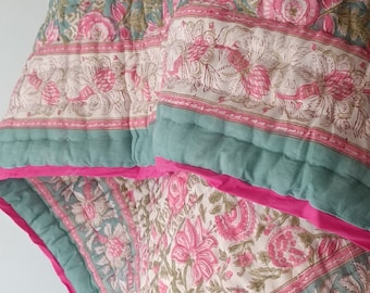Può includere: Una trapunta con motivo floreale verde e rosa con un bordo rosa. La trapunta è piegata a metà e il motivo floreale è visibile su entrambi i lati.