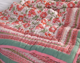 Può includere: Un piumino in cotone bianco con stampa floreale rosa e verde. Il piumino è trapuntato a griglia e ha un bordo rosa e verde.