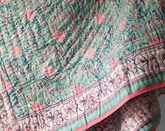Può includere: Un trapunta con motivo floreale verde e rosa con un bordo rosa. La trapunta è realizzata in cotone e ha una sensazione morbida e confortevole.