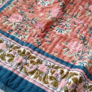 Può includere: Tessuto trapuntato con un motivo floreale nei toni del corallo, rosa, verde acqua e bianco. Il design include grandi rose rosa e dettagli botanici. Un bordo verde acqua incornicia i bordi, aggiungendo un accento di contrasto.