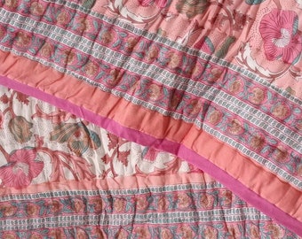 Può includere: Un trapunta rosa e bianca con motivo floreale e un bordo rosa. La trapunta è realizzata in cotone e ha un design trapuntato.
