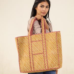 May include: A large yellow tote bag with a floral print and red trim. The bag has multiple pockets and is made of quilted fabric.