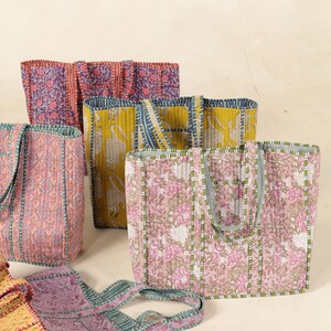 May include: Five colorful quilted tote bags with different floral and geometric patterns. The bags have green, blue, pink, yellow, and purple accents.