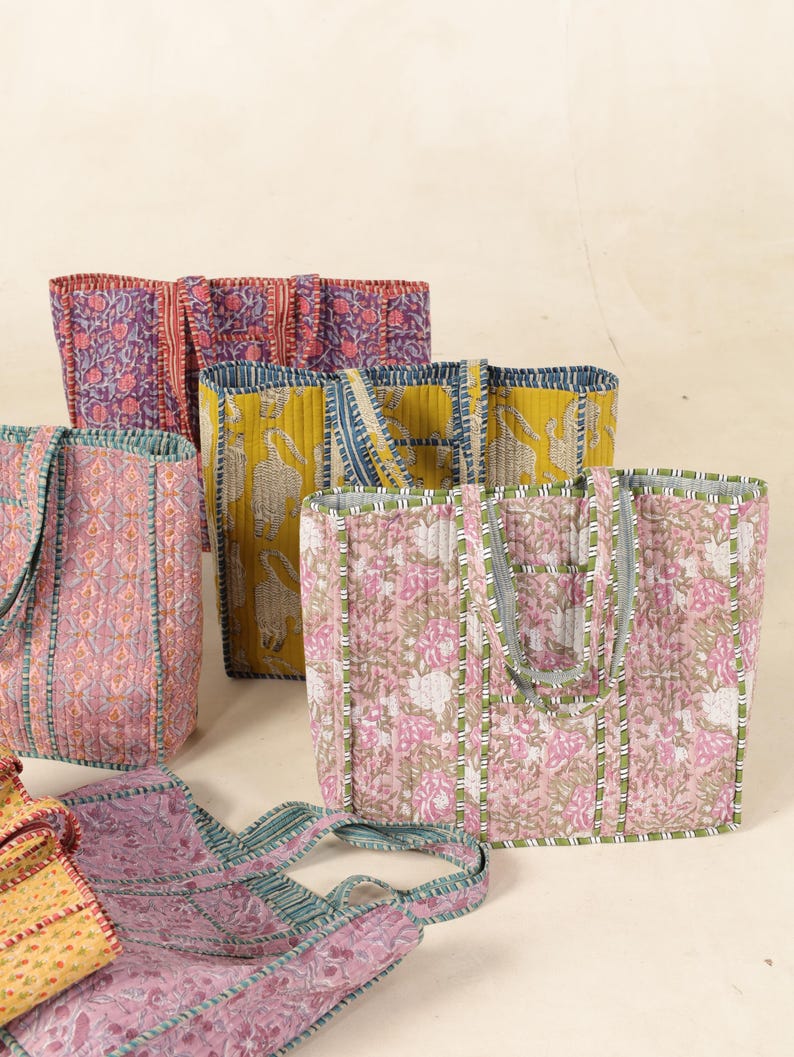 May include: Five colorful quilted tote bags with different floral and geometric patterns. The bags have green, blue, pink, yellow, and purple accents.
