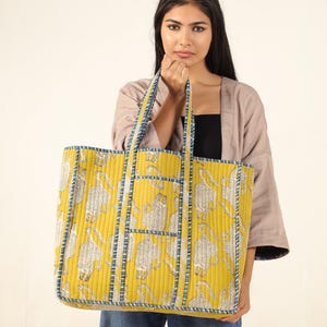 May include: A large yellow tote bag with a blue and white patterned design. The bag has a quilted texture and features a repeating pattern of stylized animals.