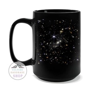 May include: Black ceramic mug with a galaxy print. The print features a swirling pattern of stars and galaxies on a black background.