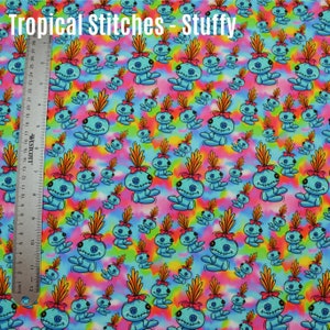 May include: A blue and white fabric with a repeating pattern of a cartoon character with a blue body, pink bow, and orange hair. The background is a tie-dye pattern with pink, blue, yellow, and green colors. The text "Tropical Stitches - Stuffy" is at the top of the fabric.