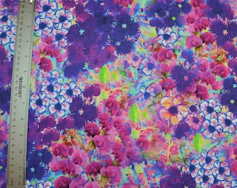 Op de afbeelding: Een kleurrijke stof met een bloemenpatroon in tinten roze, paars, blauw en groen. De stof heeft een aquareleffect en bevat verschillende bloemenvormen en -groottes.