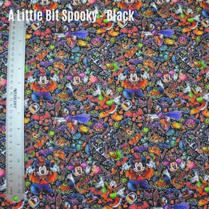 May include: Black fabric with a Halloween-themed print featuring Mickey Mouse, Donald Duck, and other Disney characters. The print includes candy, bats, pumpkins, and other Halloween imagery.