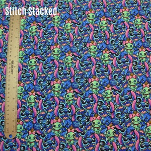 Może przedstawiać: Tkanina w kolorze niebieskim i zielonym z powtarzającym się wzorem Stitch, niebieskiego kosmity z dużymi oczami i różową kokardką, oraz zielonego kosmity z dużymi oczami i różową kokardką. Na tkaninie widnieje napis "Stitch Stacked" w lewym górnym rogu.