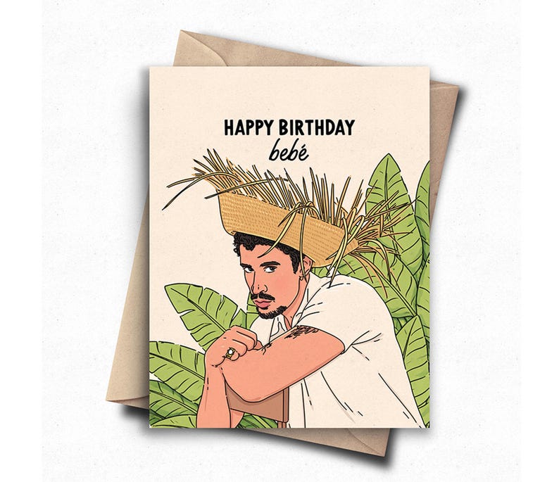 May include: Greeting card with the text "HAPPY BIRTHDAY beb&eacute;" featuring an illustration of a man wearing a straw hat. The man is depicted in a white shirt, with a tattoo on his arm, and is surrounded by green foliage. The card is inside a brown envelope.