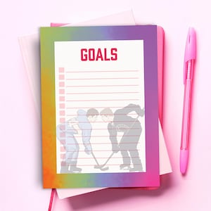 May include: A rectangular notepad with a vibrant rainbow gradient border and the word GOALS printed in red at the top. The centre features a white lined checklist with a faint illustration of two hockey players facing off on the ice.