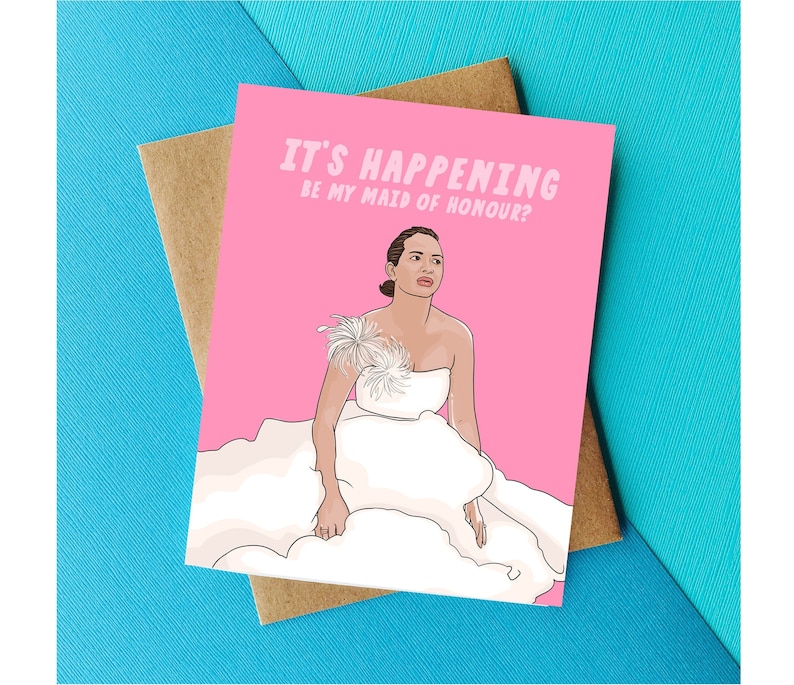 May include: A pink card with a cartoon illustration of a woman in a white wedding dress. The text on the card reads "It's happening. Be my maid of honour?"