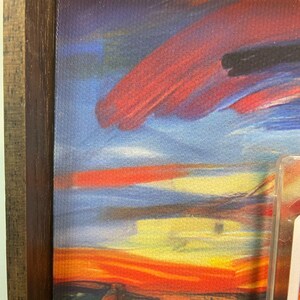 May include: A framed print of a painting with a swirling, abstract sky in shades of blue, red, yellow, and orange. The sky is painted with thick, visible brushstrokes.