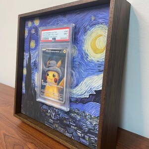May include: A framed print of Vincent van Gogh's Starry Night with a graded Pokemon card featuring Pikachu wearing a grey felt hat in the center. The card is graded a 9 and is labeled "#005 MINT".