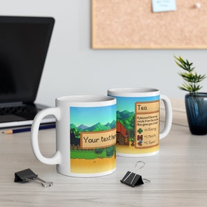 May include: Two white ceramic mugs with a pixelated video game design. One mug features a green landscape with a brown house and the text "Your text here". The other mug features a brown background with the text "Tea" and a list of benefits: "A pleasant beverage made from tea leaves. Also gives you a boost +3 Energy +1 Health +1 Speed"