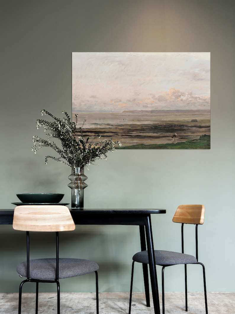 May include: A black dining table with a wood top and two black metal chairs with gray cushions. A painting of a seascape hangs on the wall behind the table.