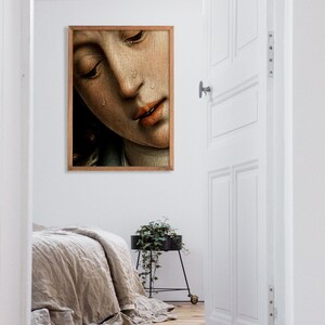 K&ouml;nnte beinhalten: Ein gerahmtes Gem&auml;lde eines Frauen Gesichts mit Tr&auml;nen, die ihr &uuml;ber die Wangen laufen. Das Gem&auml;lde ist in einem Holzrahmen und h&auml;ngt an einer wei&szlig;en Wand.
