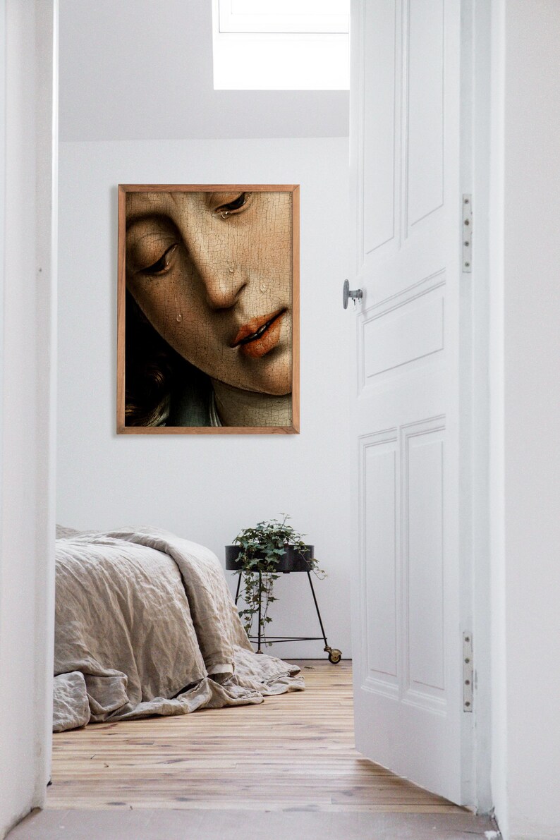 K&ouml;nnte beinhalten: Ein gerahmtes Gem&auml;lde eines Frauen Gesichts mit Tr&auml;nen, die ihr &uuml;ber die Wangen laufen. Das Gem&auml;lde ist in einem Holzrahmen und h&auml;ngt an einer wei&szlig;en Wand.
