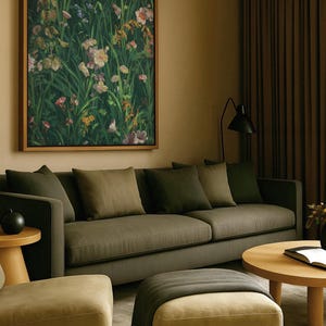 Botanical wall art featuring vibrant meadow flowers, hanging above a dark green sofa in a cozy living room with earthy tones and soft lighting.