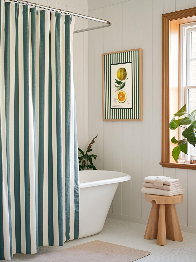 Vintage orange fruit print with green stripes framed and hanging in a cozy bathroom with a striped shower curtain. Adds a fresh, citrus-inspired accent to a cottagecore interior.