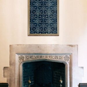 May include: A stone fireplace with a dark brick interior and two ornate brass andirons. A framed print with a blue and white geometric pattern hangs above the fireplace.