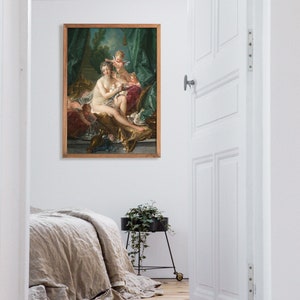 May include: A framed painting of a woman in a white dress with two cherubs. The woman is sitting on a couch with a green and gold background. The painting is in a wooden frame.