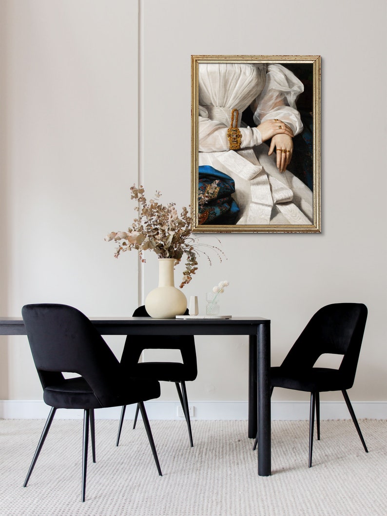 Modern dining room with a black wooden table and black chairs, behind the wall hangs an antique golden frame with an altered art print of a woman.