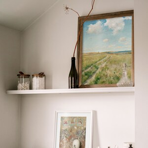 A wall niche with a shelf and a dresser with various utensils and two picture frames on it.