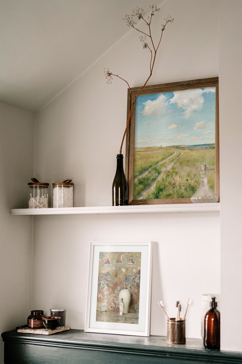 A wall niche with a shelf and a dresser with various utensils and two picture frames on it.