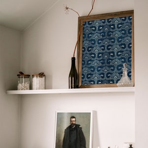 May include: A white shelf with two glass jars with lids, a dark glass bottle, and a framed print of a blue and white patterned design. Below the shelf is a black shelf with a framed portrait of a man in a dark coat, two small jars, a bowl, a container of toothbrushes, and a dark glass bottle with a pump dispenser.