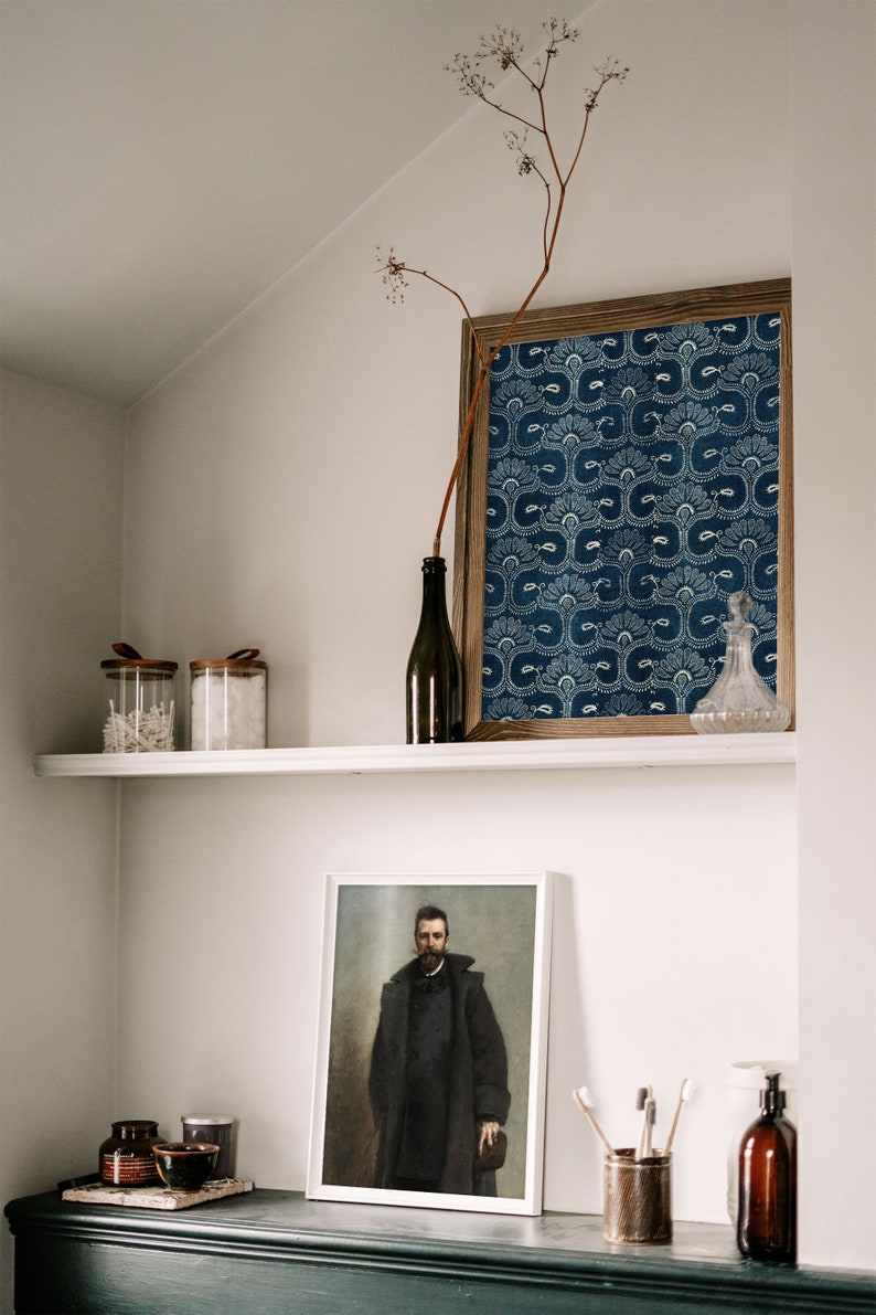 May include: A white shelf with two glass jars with lids, a dark glass bottle, and a framed print of a blue and white patterned design. Below the shelf is a black shelf with a framed portrait of a man in a dark coat, two small jars, a bowl, a container of toothbrushes, and a dark glass bottle with a pump dispenser.