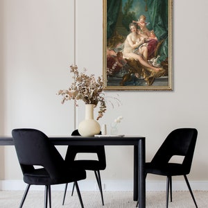May include: A framed oil painting depicting a woman reclining on a chaise lounge with two cherubs. The woman is nude and has long, flowing hair. The cherubs are dressed in white and are holding flowers. The painting is set in a garden with a fountain in the background.
