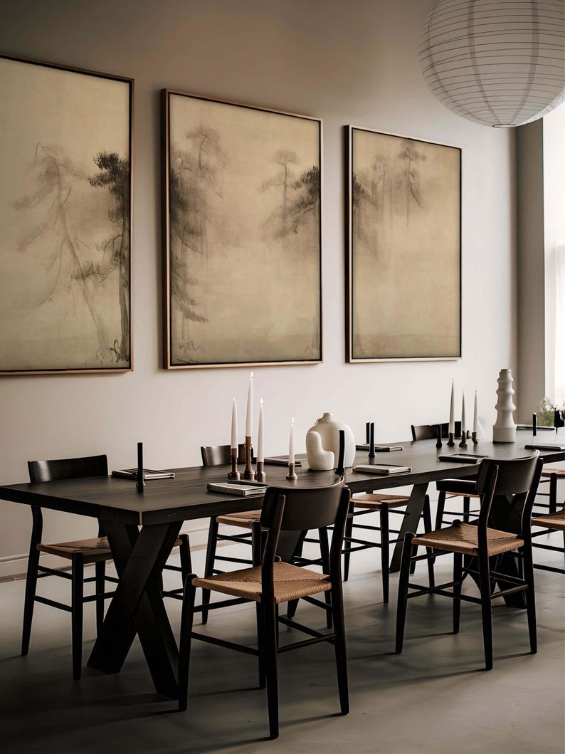 Triptych of wabi-sabi-inspired canvas wall art featuring serene, misty pine trees in earthy tones, elegantly framed and displayed in a modern dining room with minimal decor.
