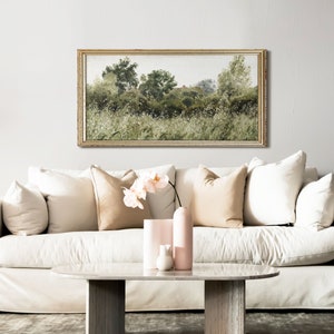 A light-filled living room with a vintage-style botanical landscape framed above a cream sofa. The wild nature scene features earthy greens and soft white highlights, adding Wabi Sabi tranquility and Japandi harmony to a modern organic space.
