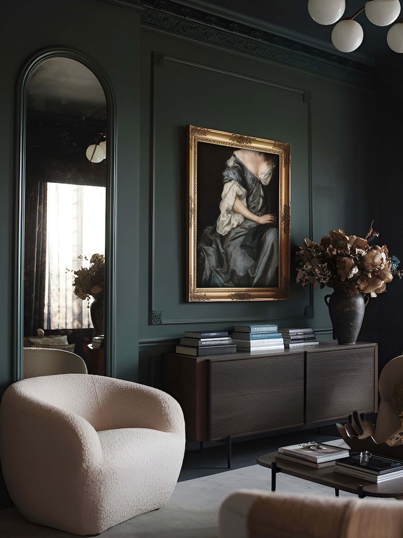 Framed Baroque portrait art print displayed on a dark green wall in a moody living room. Surrounded by sculptural furniture and dried florals, the artwork adds depth and vintage charm to modern interiors.