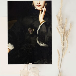 May include: A close-up of a woman's face and hand. She is wearing a black dress with a lace trim and gold earrings. The background is dark.