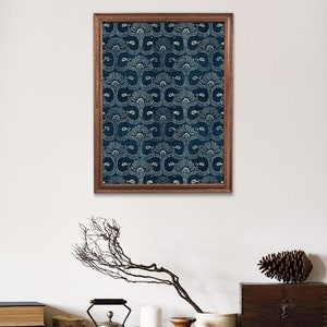 May include: A framed print of a blue and white patterned design. The print is in a wooden frame and is hanging on a white wall. There are various decorative items on a shelf below the print, including a silver teapot, candles, and a wooden vase.