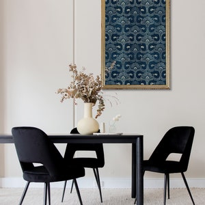 May include: A black and white patterned print in a gold frame hangs above a black dining table with two black velvet chairs. A vase with dried flowers sits on the table.