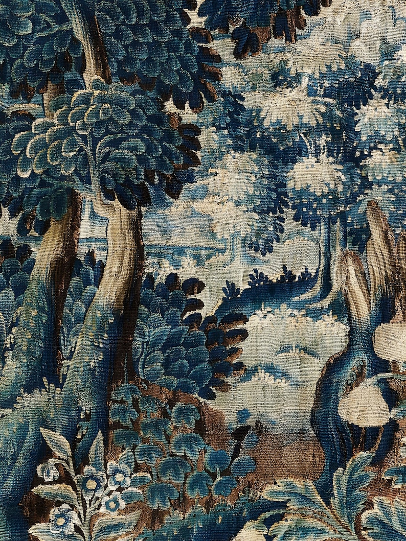 Close-up of the verdure tapestry print showing intricate woven texture, deep blue leaves and aged brown accents. The detailed botanical pattern emphasizes the historic textile look and the richness of the fine art print.