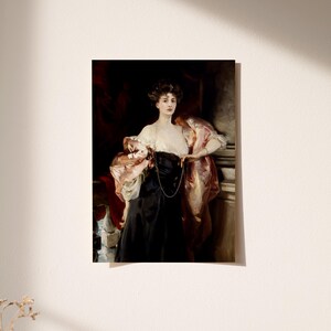 A vintage portrait of a woman in a black gown and a pink shawl draped over her arms is hung on a light-colored wall. Sunlight casts soft shadows across the wall, and a small dried branch is visible in the lower left corner.
