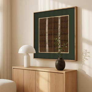 Vintage textile art print with brown woven patterns and green border, displayed above a modern sideboard with neutral decor in a bright living room.