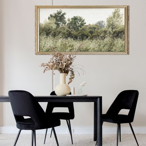 This romantic countryside painting hangs above a modern black dining table with dried florals, combining vintage textures with contemporary Japandi elegance. The soft greenery and subtle aging of the artwork reflect Wabi Sabi beauty and timeless calm.