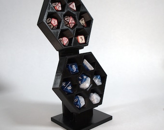Pode incluir: Torre de dados hexagonal preta com uma seção superior removível. A torre está cheia de dados de várias cores com números brancos. A torre está sobre uma base preta.